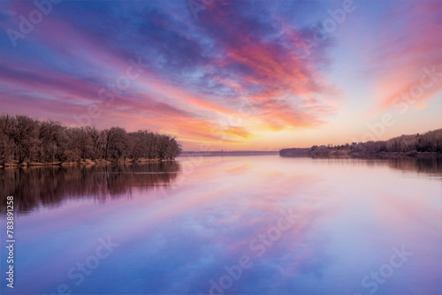 Colourful sunset reflected on a calm river, forested islands, nobody