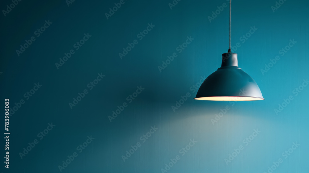 A lamp hangs against a blue wall, casting its light and illuminating the area, with space available for text or presentation. A lamp hangs against a blue wall, casting its light and illuminating the area, with space available for text or presentation.
