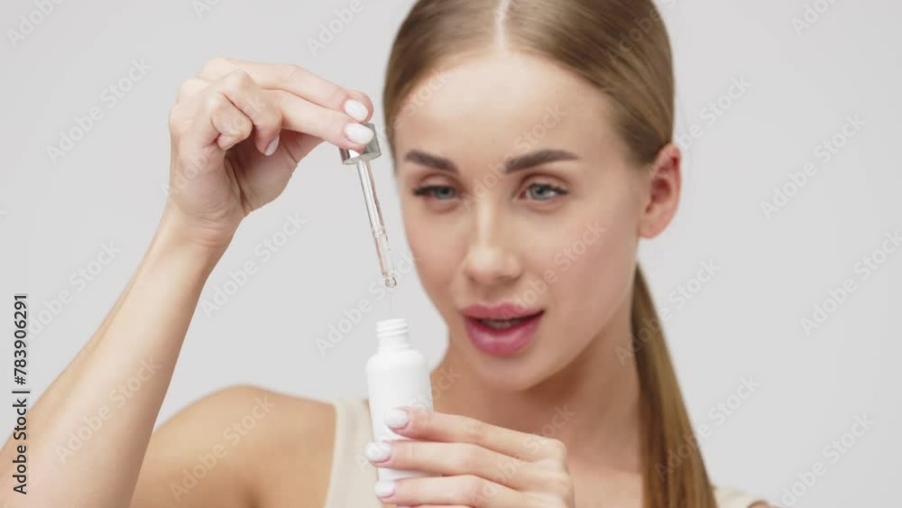 A young, beautiful model uses a facial serum or natural essence for healthy skin. The concept of natural cosmetic products and healthy, young skin. A young, beautiful model uses a facial serum or natural essence for healthy skin. The concept of natural cosmetic products and healthy, young skin.