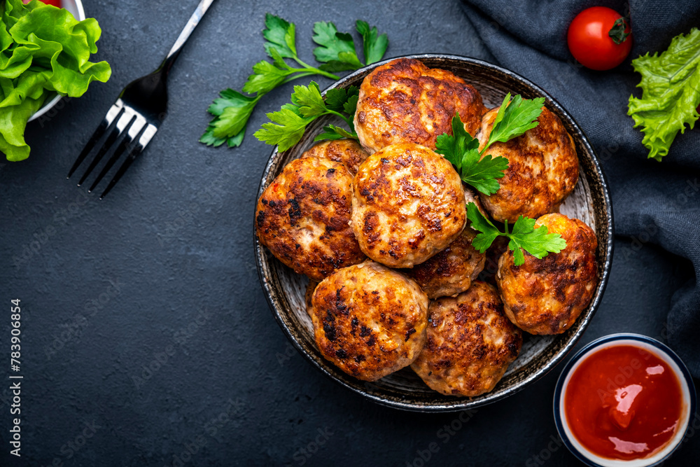 Homemade meatballs with spices and parsley in ceramic bowl, black table background, top view Homemade meatballs with spices and parsley in ceramic bowl, black table background, top view