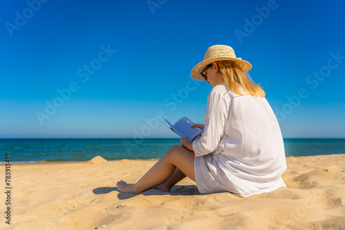 Mid-adult woman sitting on beach reading book
 #783913469