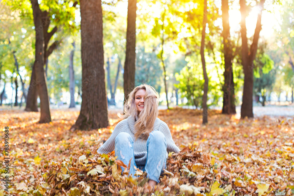 Happy blond girl posing in autumn park on yellow trees background Happy blond girl posing in autumn park on yellow trees background