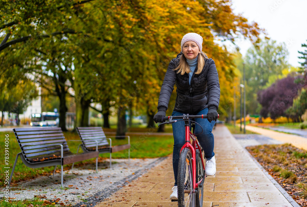 Mid-adult woman riding bicycle in city park on a rainy day
Mid-adult woman riding bicycle in city park on a rainy day