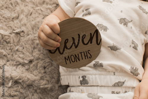 Baby holding eleven months old sign in his right hand