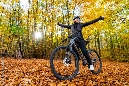 Woman riding bicycle in city forest in autumn scenery  © Jacek Chabraszewski