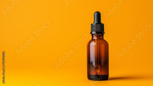   A brown glass bottle with a black top and cap is positioned against a sunny yellow background The bottle's contents are accessed by a dipper or dropper photo