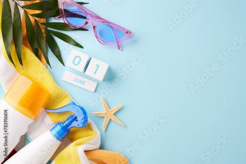 Beginning of summer concept with calendar, sunglasses, and sun protection on a sky blue background