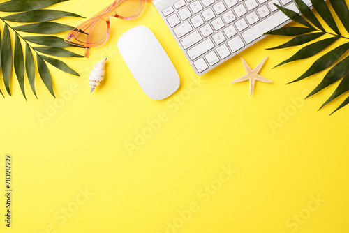 Top view of a tropical summer workspace with palm leaves on a bright yellow background