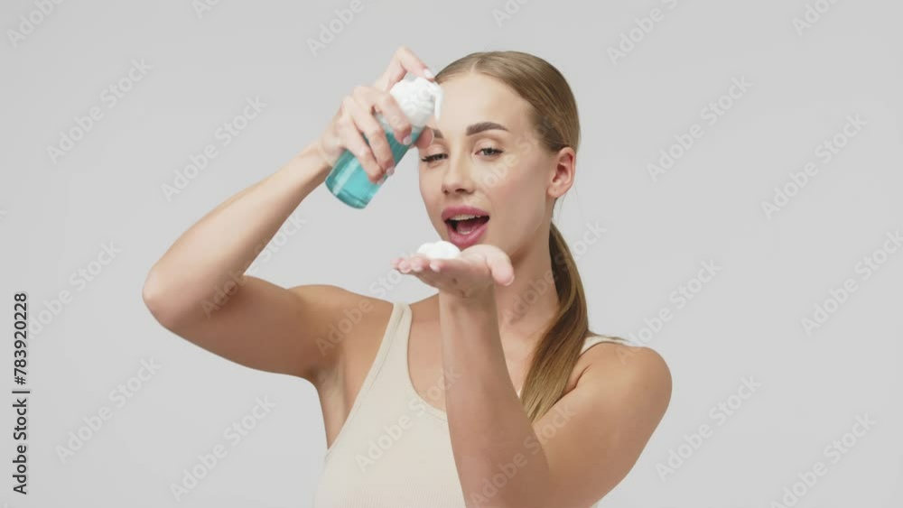 Young woman holding face wash on light studio background. Facial foam, facial cleanser, skin care cosmetics, face wash mousse. Young woman holding face wash on light studio background. Facial foam, facial cleanser, skin care cosmetics, face wash mousse.