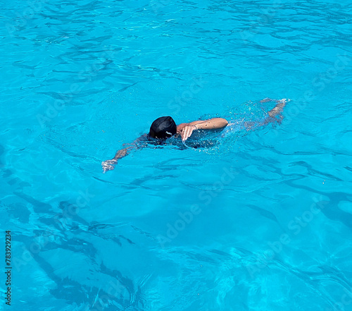 Woman with black cap swimming in a pool of blue water