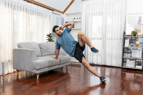 Athletic body and active sporty man using furniture for effective targeting muscle gain exercise at gaiety home exercise as concept of healthy fit body home workout lifestyle.