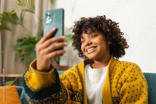 African American girl holding smartphone having video chat. Female blogger chatting with best friends in social network. Young woman having virtual meeting online chat video call at home
