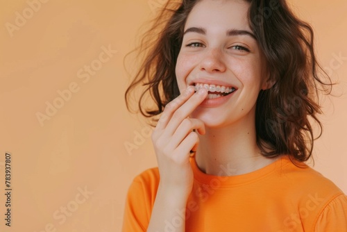 Close-up of a joyful young woman in orange, smiling with dental braces