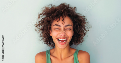 Joyful Young Woman Laughing Against a Serene Blue Background During Daytime