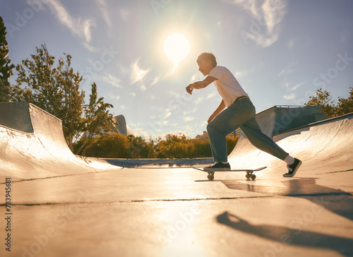  Full body of young male skater in casual outfit doing trick on skateboard riding in skate park
