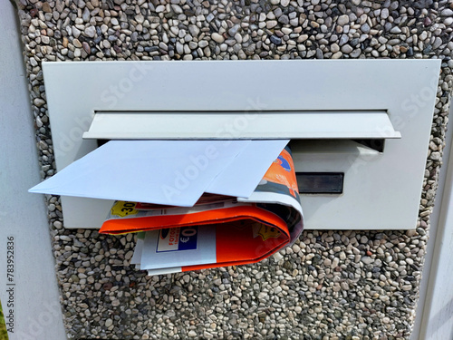 close-up - white mailbox with letters and advertising catalogs