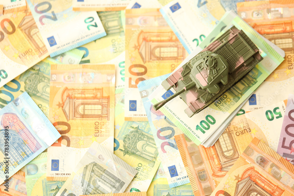 Many euro banknotes and tank. Lot of bills of European union currency and green tank close up Many euro banknotes and tank. Lot of bills of European union currency and green tank close up