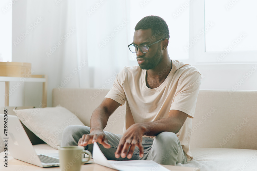 Smiling African American Man Working on Laptop in Modern Home Office, Typing and Enjoying the Freelance Lifestyle The Cozy Sofa and Stylish Interior Create a Relaxing Atmosphere, Perfect for Smiling African American Man Working on Laptop in Modern Home Office, Typing and Enjoying the Freelance Lifestyle The Cozy Sofa and Stylish Interior Create a Relaxing Atmosphere, Perfect for