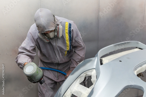 Focused Painter Spraying Car Hood in Paint Booth