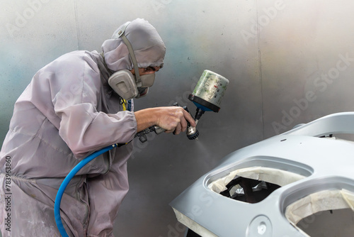 Technician Spraying Paint on Car Bumper