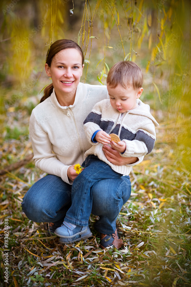 Fototapeta premium Young mother with son in autumn park