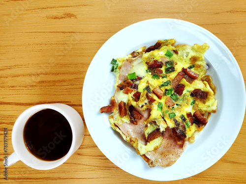 Top view of complete Omelette with bacon, ham, chesse and mug of coffee on the wooden background 