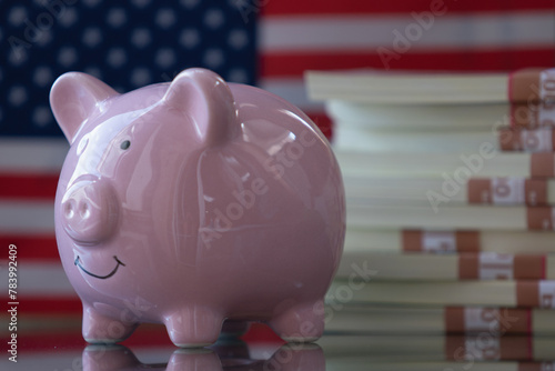 PClose up pink piggy bank with US Dollar bills against flag of United States as symbol of economy, business and investment of USA. Copy space. photo