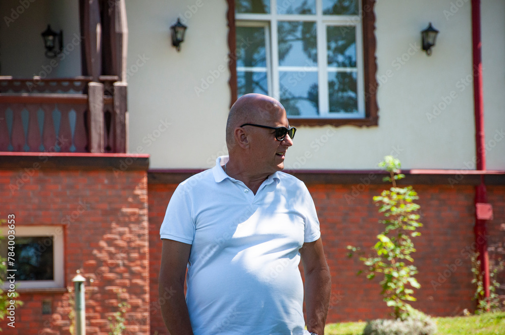 Fototapeta premium Man in sunglasses outdoor. Summer vacation. Summertime at park. Bold man relax in the park. Vacation in summer resort. Man recreation in sunglasses. Summer trend