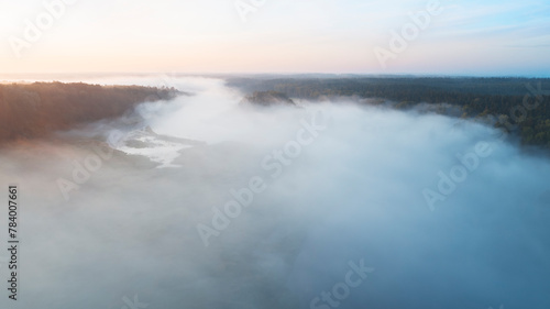 The sky is hazy and the sun is setting. The clouds are white and the water is calm