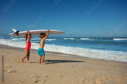 Young surfers ready to catch waves hold surfboard on shoulders