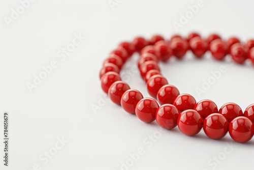 A strand of red beads on a white surface. Suitable for fashion or jewelry concepts