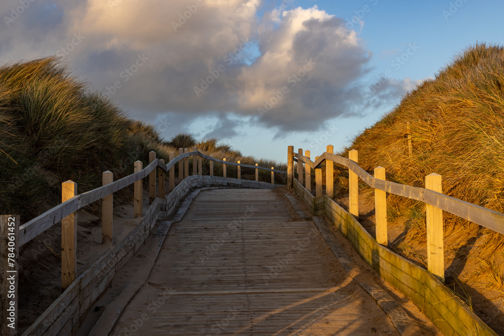 A wooden boardwalk at the coast, with evening light