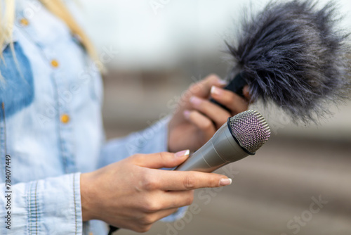 Reporter on the spot, holding microphone and dictaphone sound recorder in hand