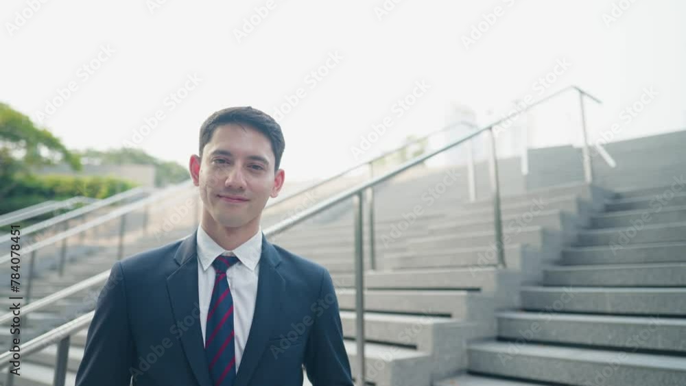 Portrait shot of an asian mixed caucasian man standing in front of modern building with slowly smiling to camera. Young cheerful happy professional entrepreneur on successful day. New Business Concept Portrait shot of an asian mixed caucasian man standing in front of modern building with slowly smiling to camera. Young cheerful happy professional entrepreneur on successful day. New Business Concept