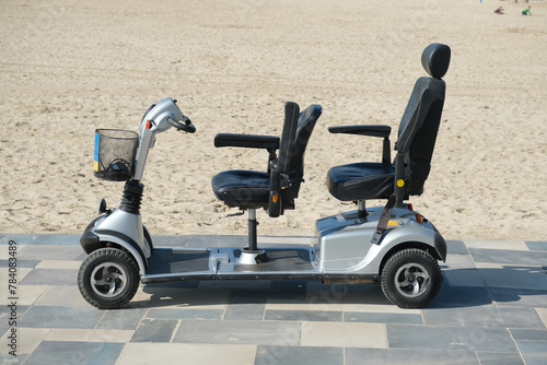 Mobility scooter parked on pavement road near sandy beach on sunny day