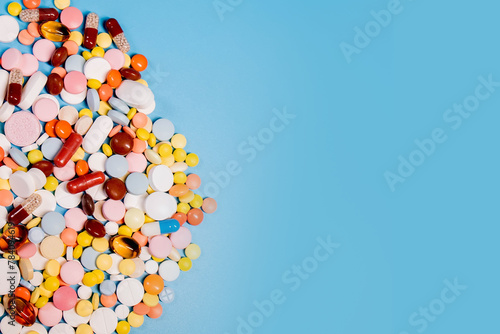 Colorful pills and capsules on blue background. Minimal medical concept. Copy space