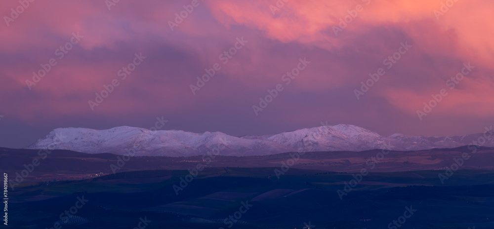 Landscape of distant snowy mountains at sunset