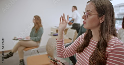 During a business training session, an engaged female participant raises her hand to ask a question, demonstrating her interest and active participation in the learning process.