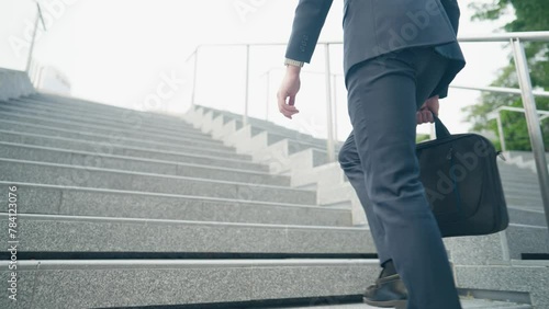 Rear view Businessmen in navy suit walk to office. man holding business handbag with business formal suit attire walking outdoor inside the city. Low angle shot business man walking up the stairs