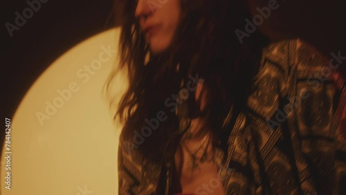 Young groovy musician with long curly hair playing the guitar during indie rock concert in dark studio with spotlight photo