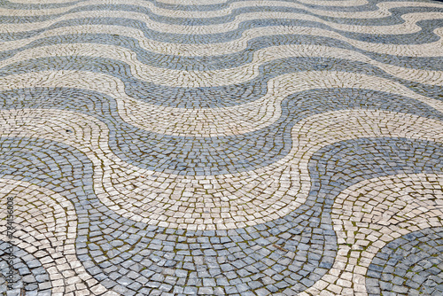 Undulating Waves of Black and White Stone Mosaic Sidewalk in Lisbon, Portugal 