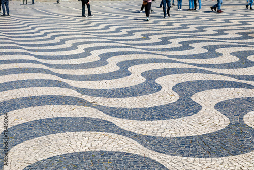 People Walking on Undulating, Dizzying Waves of Black and White Limestone Tiles on a Sidewalk in Lisbon, Portugal