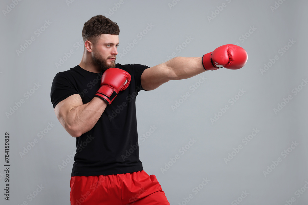Man in boxing gloves fighting on grey background - obrazy, fototapety, plakaty 