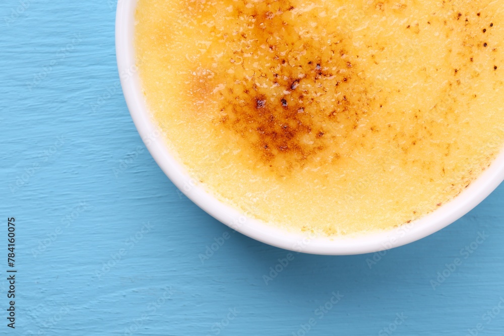 Delicious creme brulee in bowl on light blue wooden table, top view Delicious creme brulee in bowl on light blue wooden table, top view