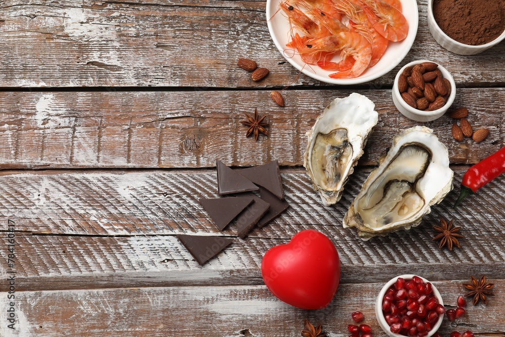 Natural aphrodisiac. Different food products and heart model on wooden table, flat lay. Space for text