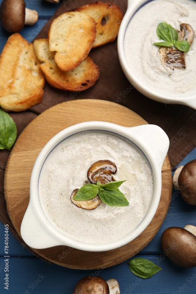 Delicious mushroom soup in ceramic pots and fresh ingredients on blue wooden table, flat lay Delicious mushroom soup in ceramic pots and fresh ingredients on blue wooden table, flat lay