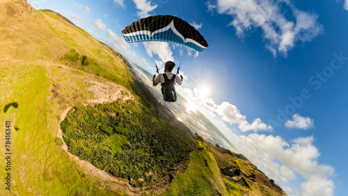 Extreme paragliding pilot soaring in the New Zealand beach at sunset. Adventure concept