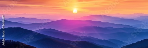 The setting sun casts an orange and purple glow over the layered mountains, creating a breathtaking panoramic view