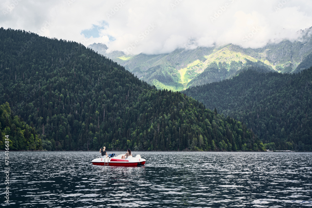 Young woman on the paddleboat in a center of a lake surrounding by the mountains Young woman on the paddleboat in a center of a lake surrounding by the mountains