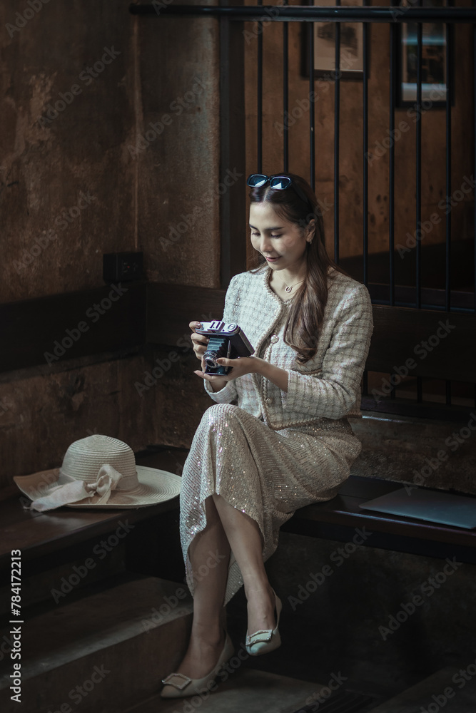 Obraz premium Beautiful young Asian woman brunette woman wearing fashion clothes casual dress and camera. Portrait fashion model in beige clothes at traditional architecture old wall vintage building. Retro style.